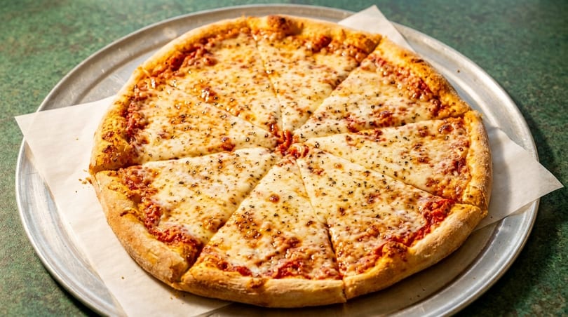 A whole cheese pizza, cut into eight slices, on a metal pan with parchment paper.